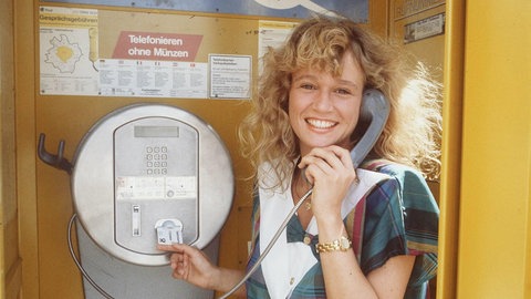 Eine Frau telefoniert in einer Tezefonzelle mit einer Telefonkarte: Das Kartentelefon galt 1987 als technische Revolution, ermöglichte es doch das Telefonieren ohne Münzen