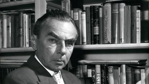 Erich Kästner 1959 vor einem Bücherregal