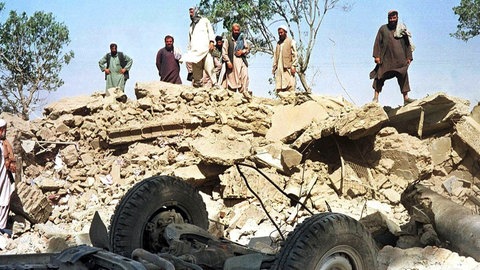 Afghanen blicken am 9.10.2001 auf die Trümmer des Gebäudes der von den Vereinten Nationen (UN) finanzierten Minenräumorganisation Afghan Technical Consultants in Kabul.