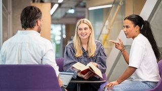 Mitarbeitende tauschen sich bei der Arbeit aus