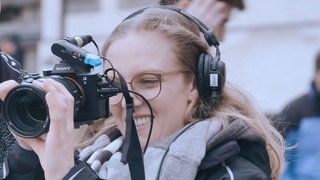 Mediengestalterin beim Außendreh mit einer Kamera