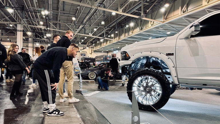 Ein Besucher der Essen Motor Show begutachtet ein besonders massiges Fahrzeugmodell.