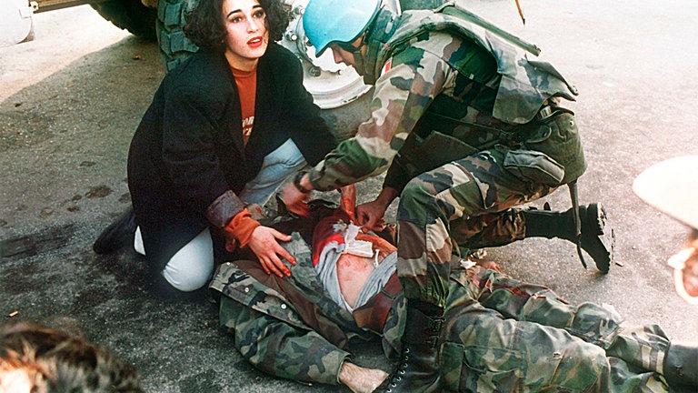 Sarajevo, Bosnien, 1994: Eine Passantin leistet mit einem französischen UN-Soldaten Erste Hilfe, nachdem ein bosnischer Soldat auf offener Straße in Sarajevo angeschossen wurde. Er starb Minuten später.