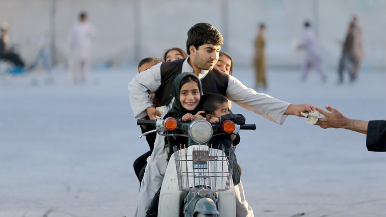 Kandahar, Afghanistan, 2013: Ein Vater bezahlt Eintritt für einen Vergnügungspark.