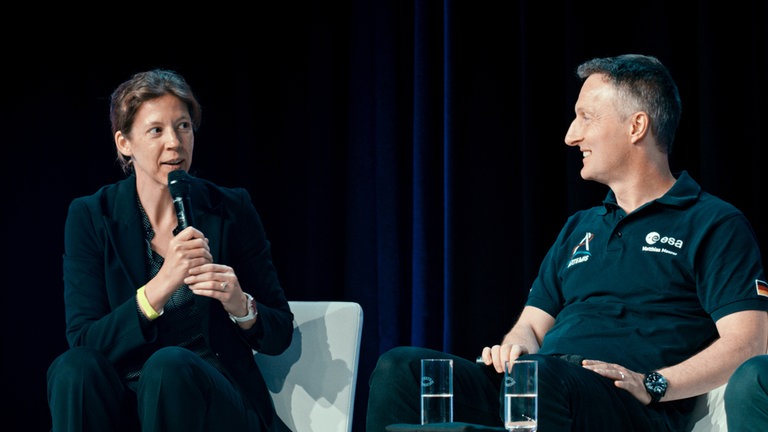 Hélène Huby spricht auf einer Konferenz mit dem deutschen Astronauten Matthias Maurer
