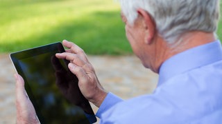 Ein älterer Mann, der über ein Tablet wischt