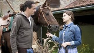 Matthias und Jenny stehen auf dem Gelände von Matthias' Gestüt bei einem Pferd