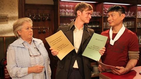 Leni, Dr. Kaiser und Tu stehen hinterm Tresen im Löwen