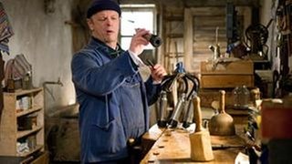 Toni steht im Brunnengang und reinigt das Melkgeschirr