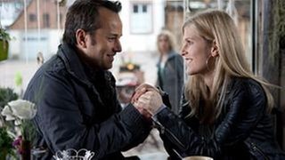 Murat sitzt mit einer fremden Frau Händchen haltend in einem Café, Kati beobachtet die beiden von draußen