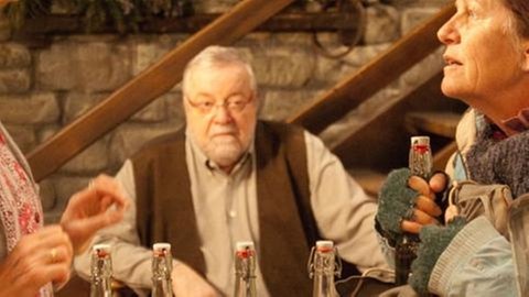 Lioba und Johanna stehen sich im Hofladen gegenüber, im Hintergrund sitzt Hermann