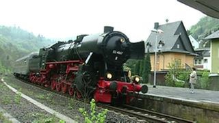 Eine Eisenbahn fährt in einen Bahnhof ein.
