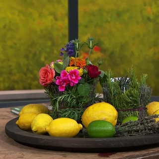 Tischdeko aus Kräutern, Zitronen und bunten Sommerblumen