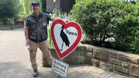Ein Mann hält das wiederaufgetauchte Storchen-Schild von Tripsdrill in den Händen.