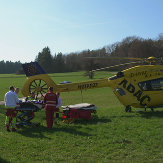 Die Heli-Retter transportieren einen verletzte Person in den Rettungshelikopter.