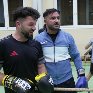 Luan steht mit seinen Boxkollegen im Studio, bereit für das Training mit Boxhandschuhen.