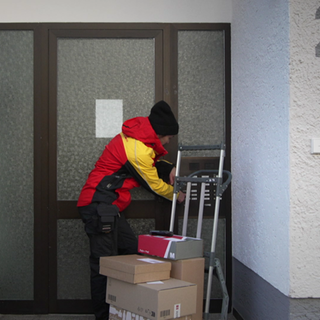 Paketbotin Nadine stellt Pakete an der Haustüre zu.