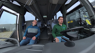 Ein Fahrlehrer begleitet einen Fahrschüler beim Steuern eines Busses.
