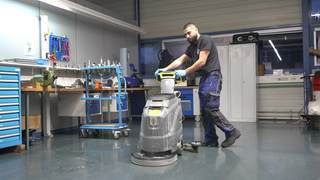 Ein junger Mann schiebt eine Reinigungsmaschine.