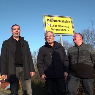 Hans Frei (3. v.l.) steht mit seinen Söhnen vor dem Ortsschild mit dem Aufdruck Memprechtshofen. Die vier singen gemeinsam in einem Chor.
