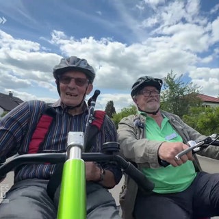 Zwei Männer fahren mit einer Rikscha durch einen Ort.