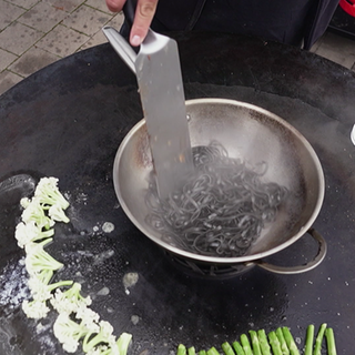 Pasta werden im Wok auf einem Grill gekocht