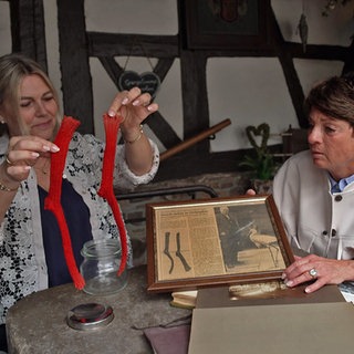 Silke Becker aus Pfinztal und Sonja Faber-Schrecklein sitzen am Tisch und schauen ein Fotoalbum an.