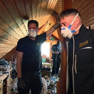 Entrümpler Raphael Uhland und Dejan Čakalo bei ihrer Arbeit in einem Messie-Haus. Sie tragen Masken.