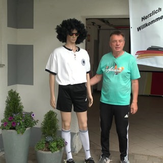 Fußballfan Peter Saß neben einer Puppe in Fußballklamotten.