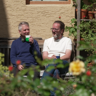 Stefan Lipka und Martin Wünsche sitzen in ihrem Garten und genießen ein Getränk und den Anblick ihrer Arbeit.