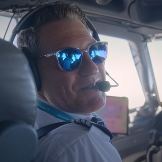 Pilot sitzt mit Sonnenbrille im Cockpit