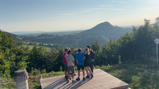 Die Wandergruppe Wandersocken steht auf einer Aussichtsplattform und schaut in die Ferne. Beim gemeinsamen Wandern werden aus Fremden oft Freunde.