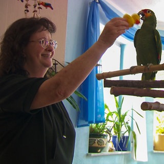 Eine Frau spielt mit einem Papagei. 