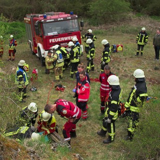 Viele Rettungskräfte stehen am Einstieg zu einer unterirdischen Höhle. Auch die Feuerwehr ist vor Ort.