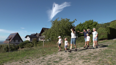 Eine Gruppe Menschen wandert über eine Bergkuppe bei Sasbachwalden.