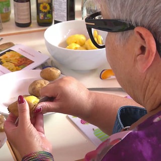 Eine Frau schält Kartoffeln.