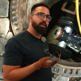 Mann steht vor einem Kanalroboter