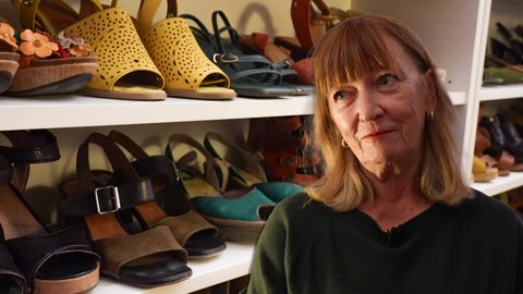 Frau steht vor einem Bücherregal voller Schuhe