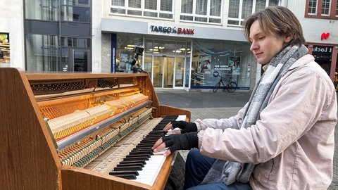 Straßenpianist sitzt in der Trierer Fußgängerzone am Klavier.