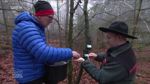 Zwei Männer bereiten Wildkameras im Wald vor