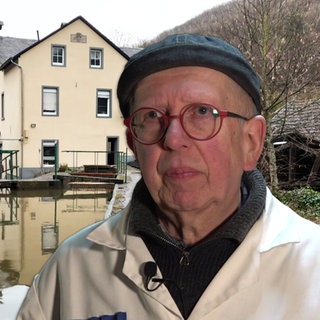 Mann steht vor einer alten Mühle