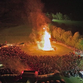 Bis zu 4.000 Gäste stehen um das riesige Maifeuer in Alpenrod herum
