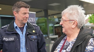 Polizist steht neben einer Seniorin
