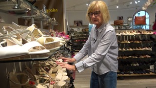 Frau sortiert ein Schuhregal