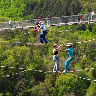 Slackliner balancieren neben der Geierlay-Brücke.