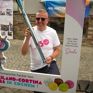 Mann steht mit einer olympischen Fackel in Cochemer Innenstadt.