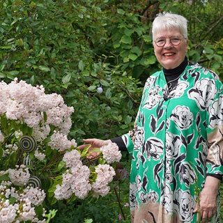 Monika Dörner neben blühenden Pflanzen in ihrem verwunschenen Garten.