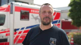 Mann seht vor einem Rettungsfahrzeug