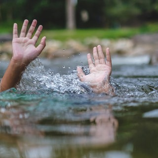 Zwei Hände strecken sich aus dem Wasser empor