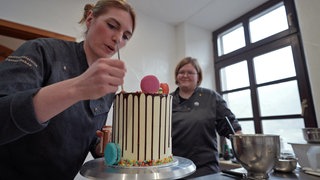 Konditorin Theresa Goka Dehen verpasst einer Torte den letzten Schliff